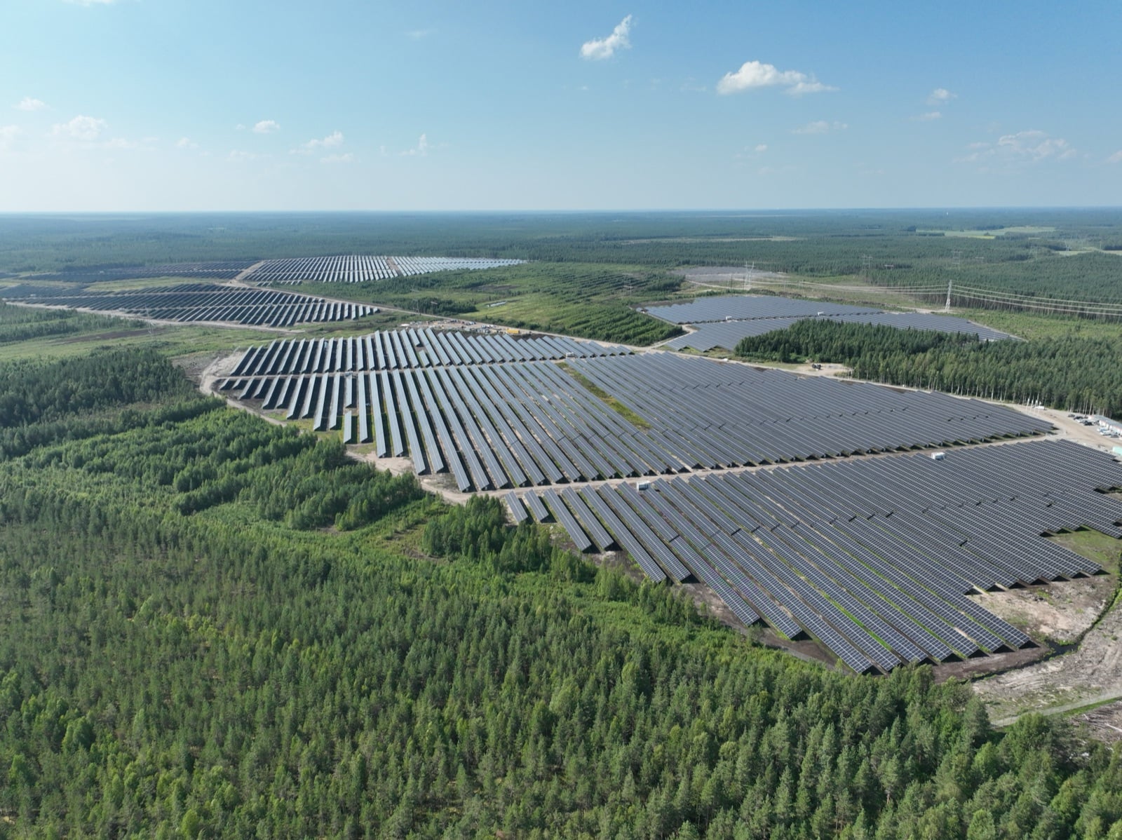 Aerial view of the Isosuo solar power plant in Finland, rows of panels set in forest under a clear sky
